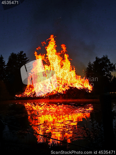 Image of Flames of a huge bonfire at night near lake