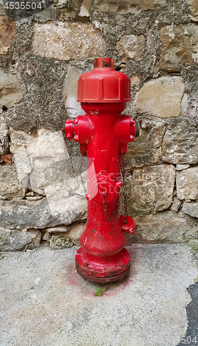 Image of Red fireplug against a stone wall 
