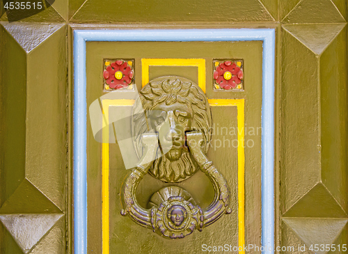 Image of Old metal doorknob in the shape of lion head on old wooden door
