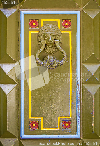 Image of Old metal doorknob in the shape of lion head on old wooden door