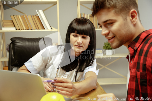 Image of Smiling nutritionist showing a healthy diet plan to patient