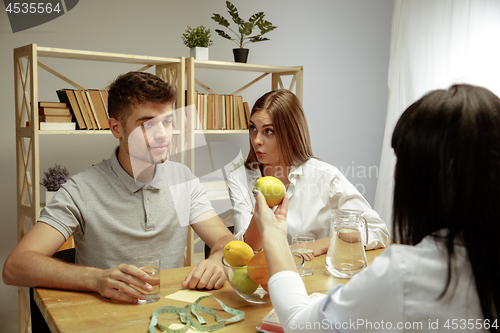 Image of Smiling nutritionist showing a healthy diet plan to patient