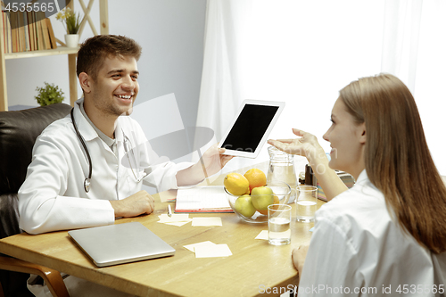 Image of Smiling nutritionist showing a healthy diet plan to patient