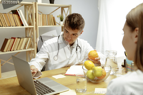 Image of Smiling nutritionist showing a healthy diet plan to patient