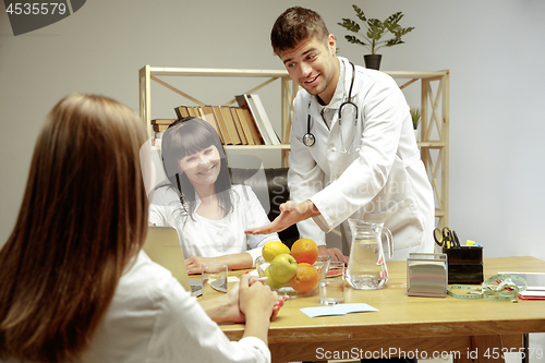 Image of Smiling nutritionists showing a healthy diet plan to patient