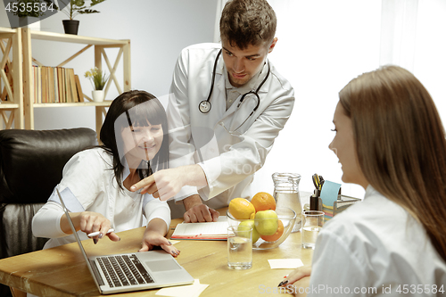 Image of Smiling nutritionists showing a healthy diet plan to patient