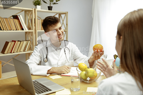 Image of Smiling nutritionist showing a healthy diet plan to patient
