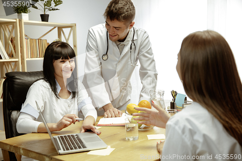 Image of Smiling nutritionists showing a healthy diet plan to patient