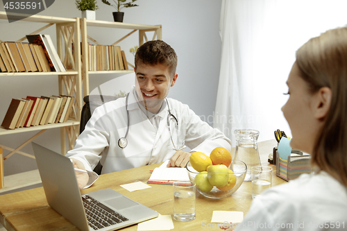 Image of Smiling nutritionist showing a healthy diet plan to patient