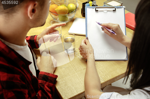 Image of Smiling nutritionist showing a healthy diet plan to patient