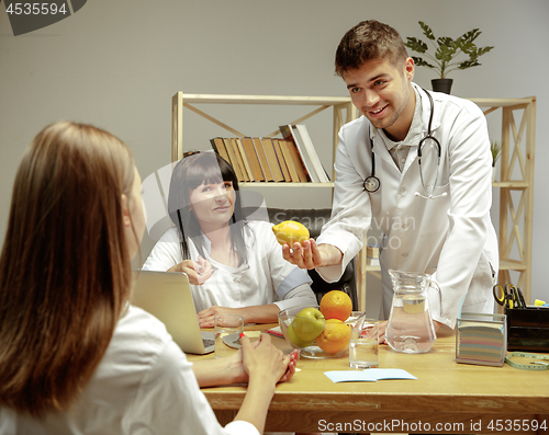 Image of Smiling nutritionists showing a healthy diet plan to patient