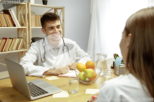 Image of Smiling nutritionist showing a healthy diet plan to patient