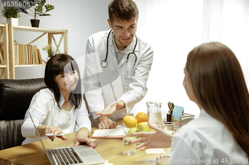 Image of Smiling nutritionists showing a healthy diet plan to patient