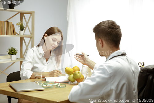 Image of Smiling nutritionist showing a healthy diet plan to patient