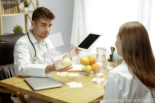 Image of Smiling nutritionist showing a healthy diet plan to patient