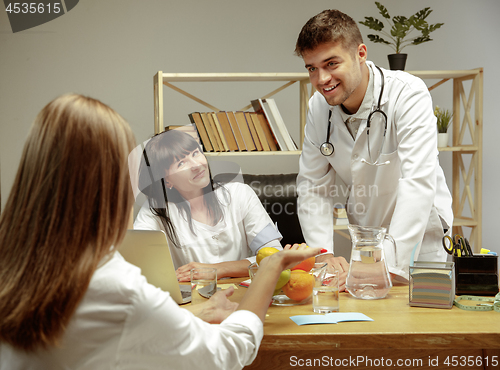 Image of Smiling nutritionists showing a healthy diet plan to patient