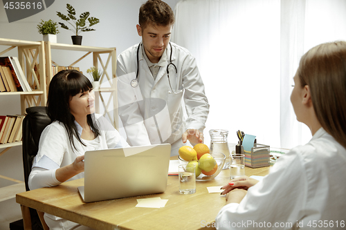 Image of Smiling nutritionists showing a healthy diet plan to patient