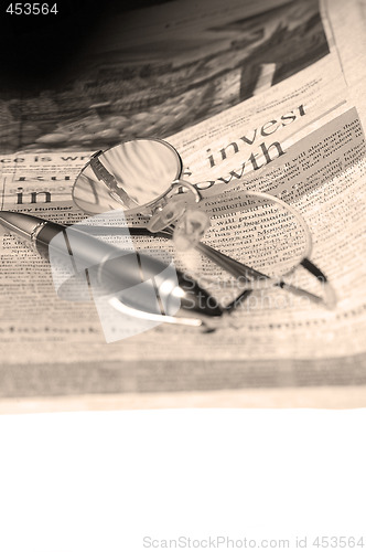 Image of pen and glasses and newspaper