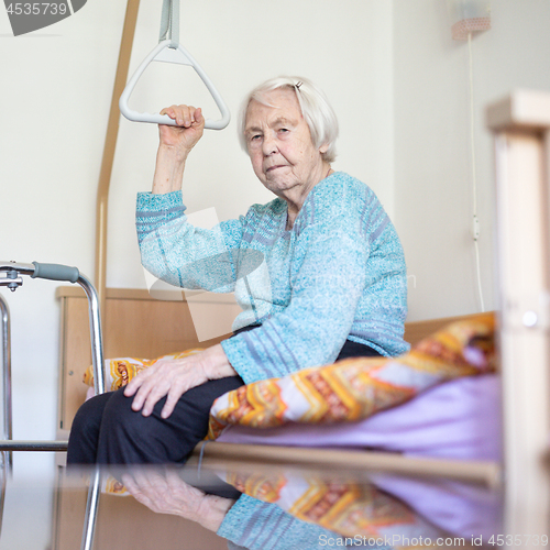 Image of Elderly 96 years old woman sitting on medical bed in hospic.