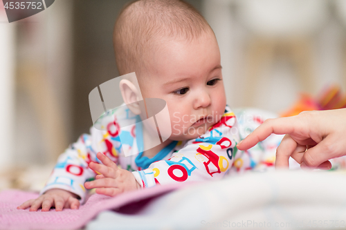 Image of newborn baby boy playing on the floor