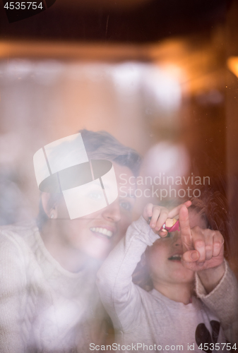 Image of young mother and little cute daughter playing near the window