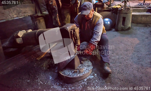 Image of blacksmith workers using mechanical hammer at workshop