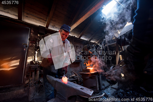 Image of blacksmith manually forging the molten metal