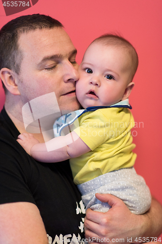 Image of portrait of happy young father holding baby isolated on red