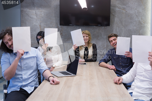 Image of startup business team holding a white paper over face