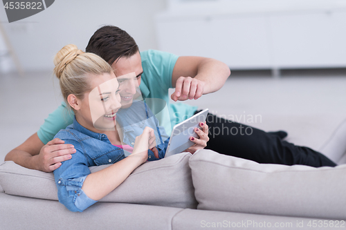 Image of couple relaxing at  home with tablet computers