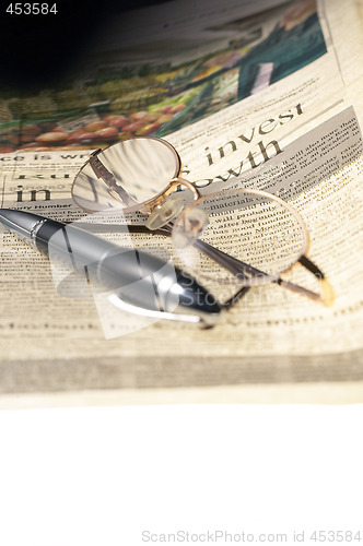 Image of pen and glasses and newspaper