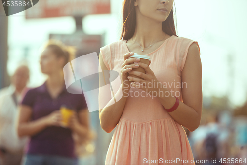 Image of Beautiful girls holding paper coffee cup and enjoying the walk in the city