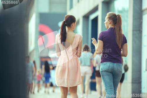 Image of Beautiful girls holding paper coffee cup and enjoying the walk in the city