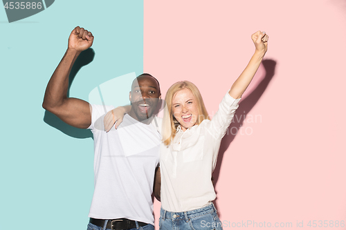 Image of We won. Winning success happy afro man and woman celebrating being a winner. Dynamic image of caucasian female and male model on pink studio.