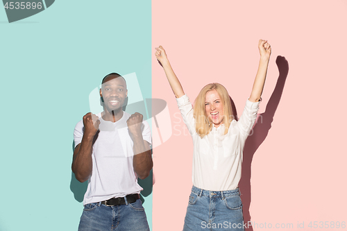 Image of We won. Winning success happy afro man and woman celebrating being a winner. Dynamic image of caucasian female and male model on pink studio.