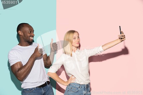 Image of Mixed raced couple of students taking common selfie with phone. Caucasian girl and her African boyfriend posing at studio .