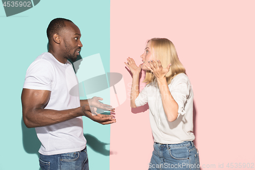 Image of Beautiful female and male portrait on pink and blue studio backgroud. The young emotional couple