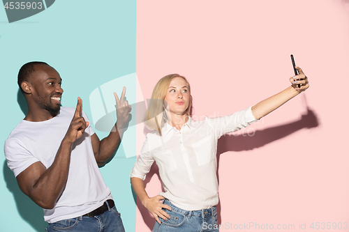 Image of Mixed raced couple of students taking common selfie with phone. Caucasian girl and her African boyfriend posing at studio .