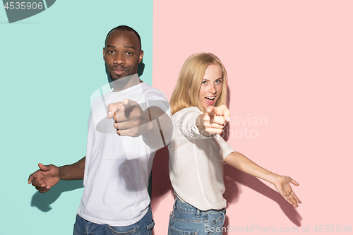 Image of The happy couple point you and want you, half length closeup portrait on studio background.