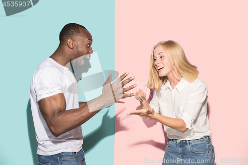 Image of Beautiful female and male portrait on pink and blue studio backgroud. The young emotional couple