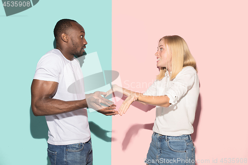 Image of Beautiful female and male portrait on pink and blue studio backgroud. The young emotional couple