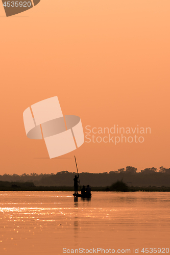 Image of Men in a boat on a river silhouette