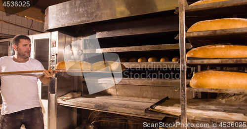 Image of bakery worker taking out freshly baked breads