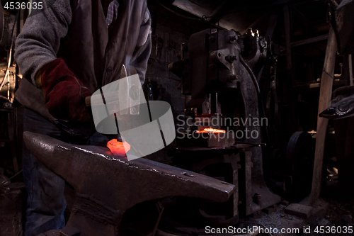 Image of blacksmith manually forging the molten metal