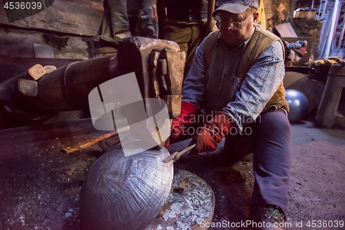 Image of blacksmith workers using mechanical hammer at workshop