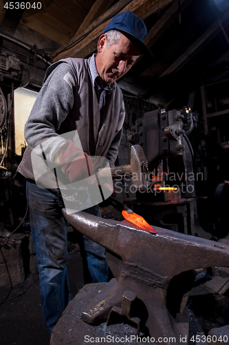 Image of blacksmith manually forging the molten metal