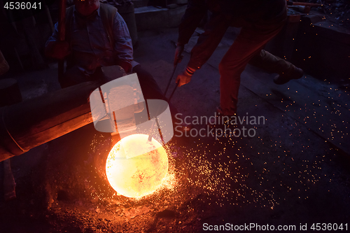 Image of blacksmith workers using mechanical hammer at workshop