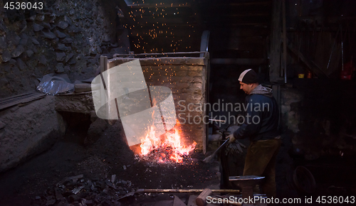 Image of young traditional Blacksmith working with open fire