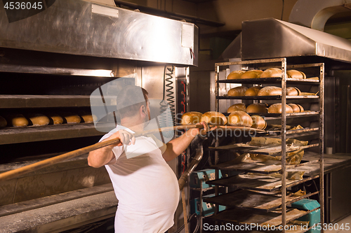 Image of bakery worker taking out freshly baked breads