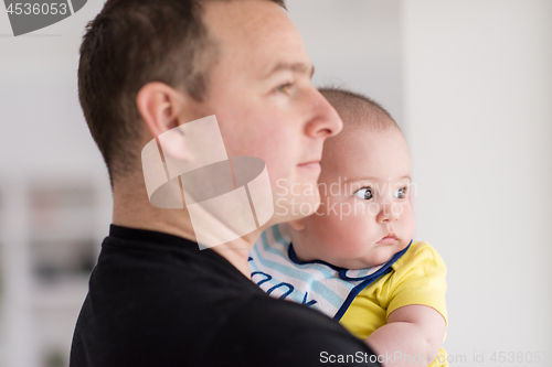 Image of young father holding baby near the window at home